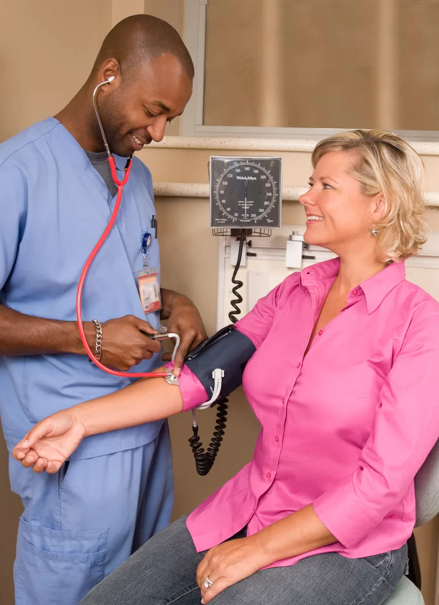 A certified nursing assistant checking a patient's blood pressure
