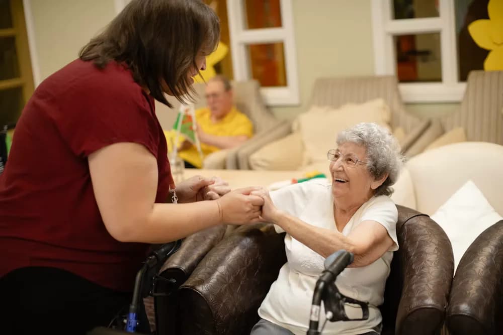 A caregiver warmly holding hands with an elderly client